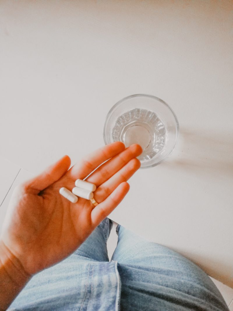 magnesium supplements (white capsules) in a woman's hand