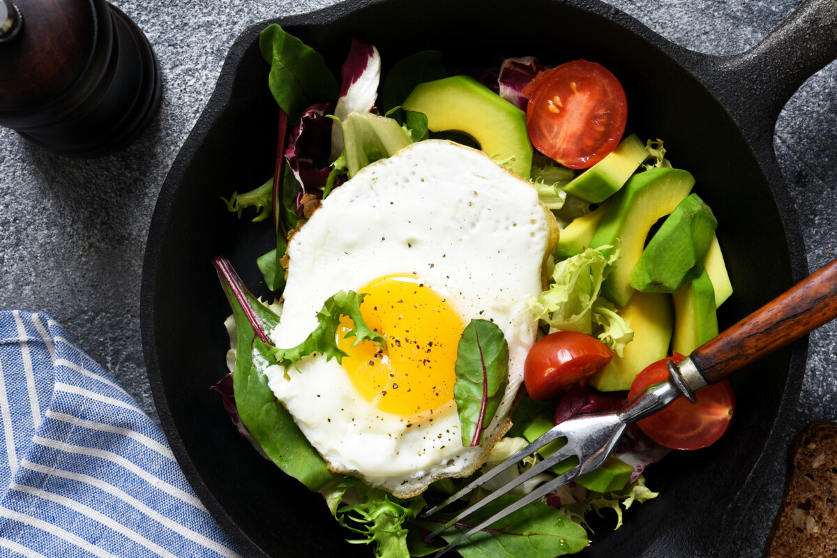 Warm Breakfast salad with tomatoes and avocado, fried in a pan for breakfast.